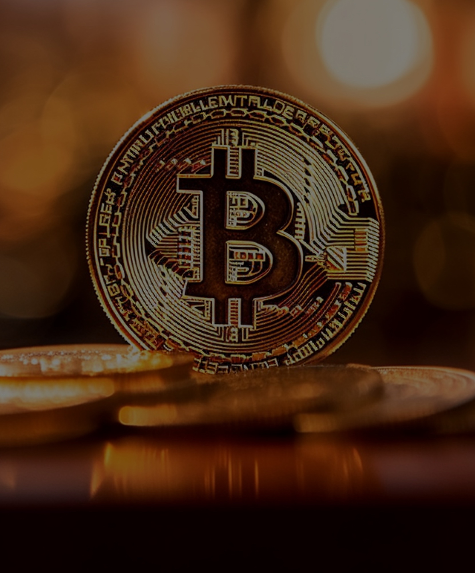 An image of a single bitcoin on a pile of gold coins with shinny light background